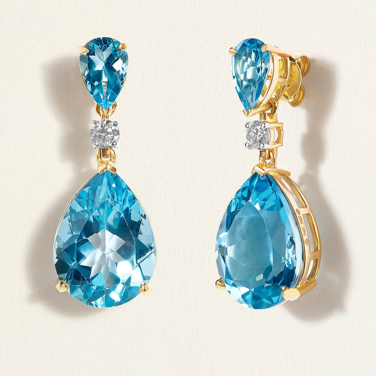 Pair of blue swiss topaz  teardrop earrings  in gold on a light background