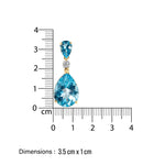 Jewelry earring with blue gemstones and gold accents, shown with a ruler for scale on a white background.