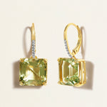 Gold huggies earrings with green amethyst gemstones on a light beige background