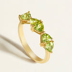 Gold stacking birthstone ring with green peridot gemstones on a light background
