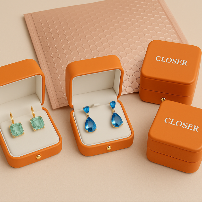Orange jewelry boxes with earrings on a beige background
