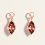 Rose gold earring charms with pink tourmalines gemstones on a light beige background