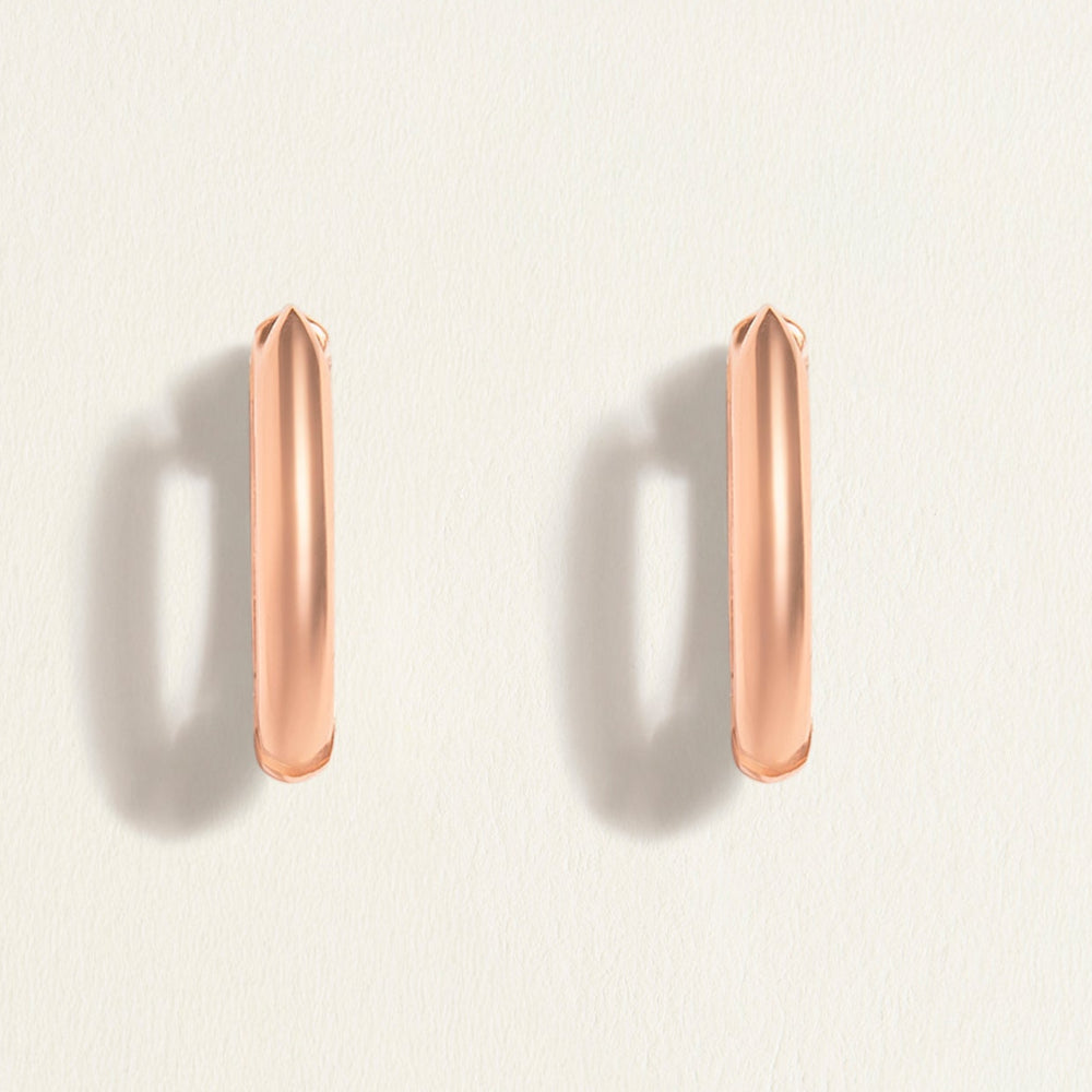 Rose gold hoop earrings on a light beige background