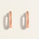 Rose gold hoop earrings on a light beige background