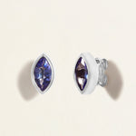 Pair of white gold earrings studs with blue tanzanites gemstones on a light beige background