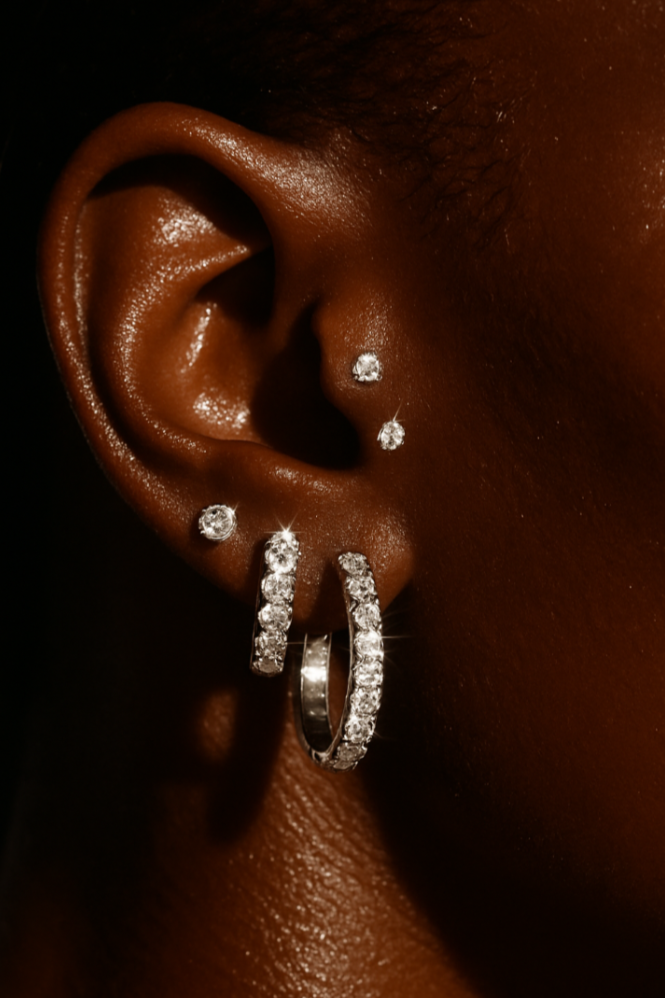Close-up of an ear wearing multiple diamond earrings on a dark background