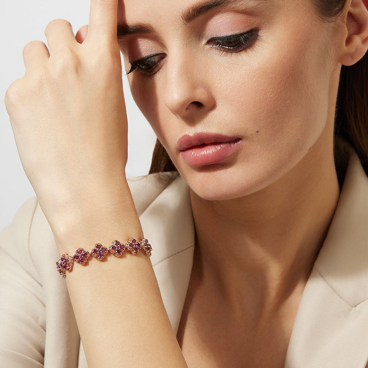 Woman wearing a clover rhodolite bracelet with a neutral background