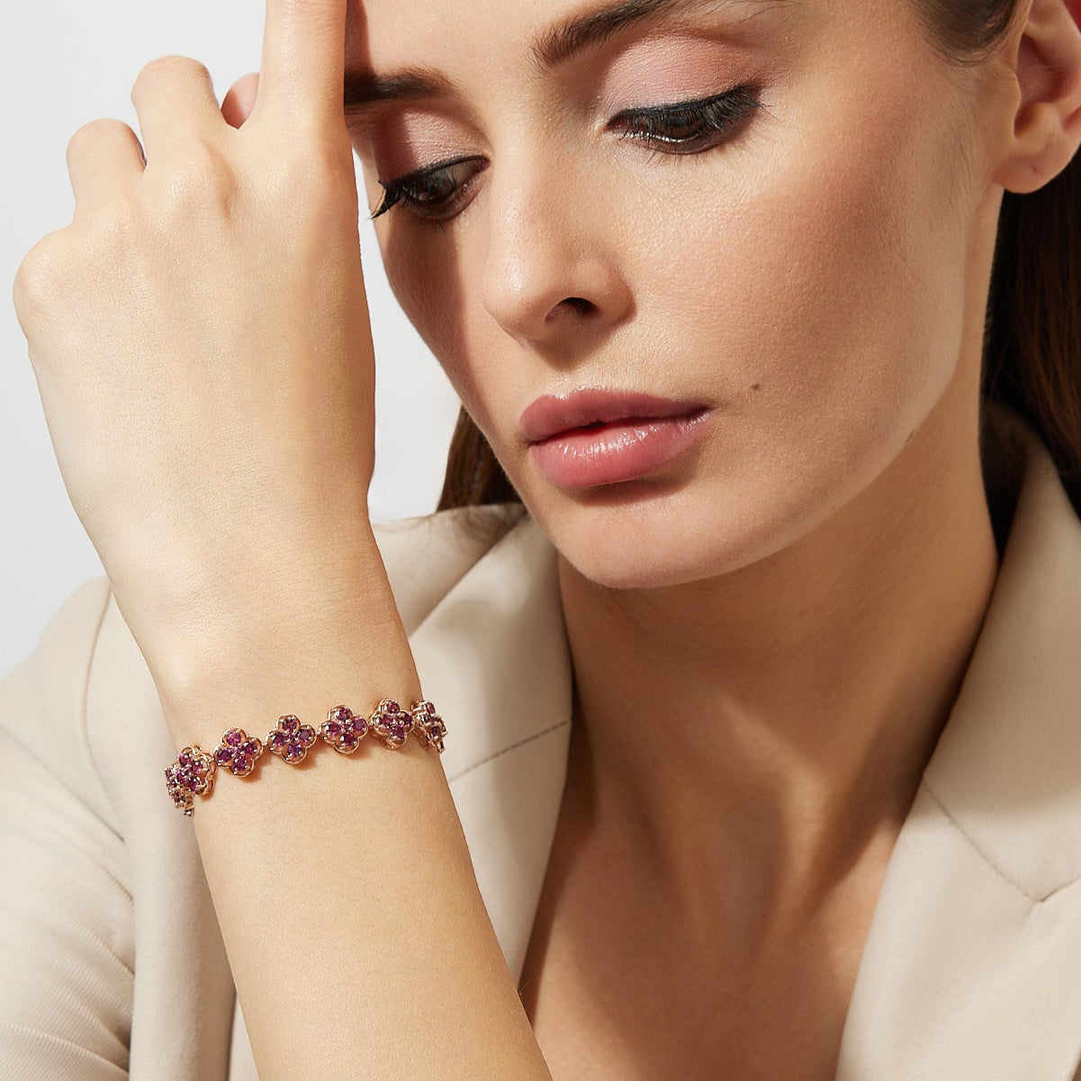 Woman wearing a clover rhodolite bracelet with a neutral background