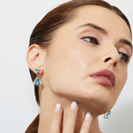 Woman wearing swiss blue topaz  in trillion drop  earrings with a neutral background