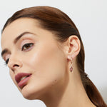 woman wearing a rose gold huggies earring with a marquise maroon tourmaline drop