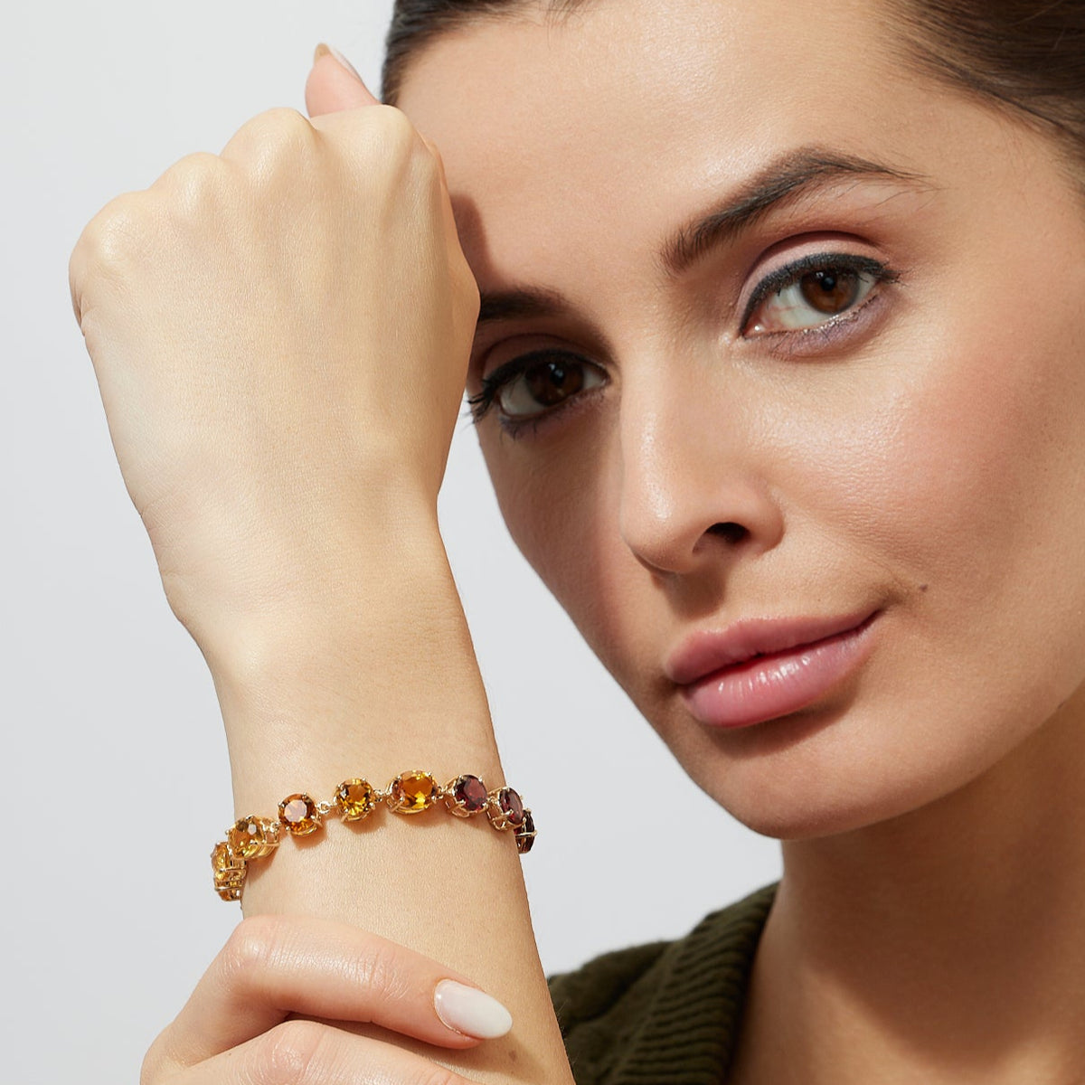 Woman wearing a gold bracelet with a ombre orange yellow citrine gemstones