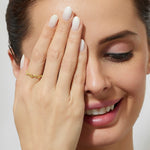 woman wearing a thin eternity stacking ring in gold and peridots