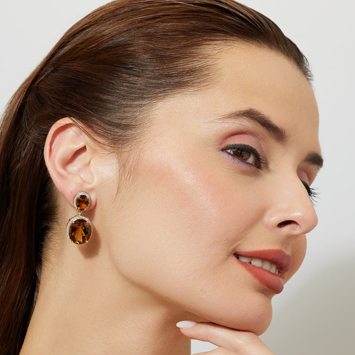 woman wearing deep orange brown gemstone earring with diamond and gold